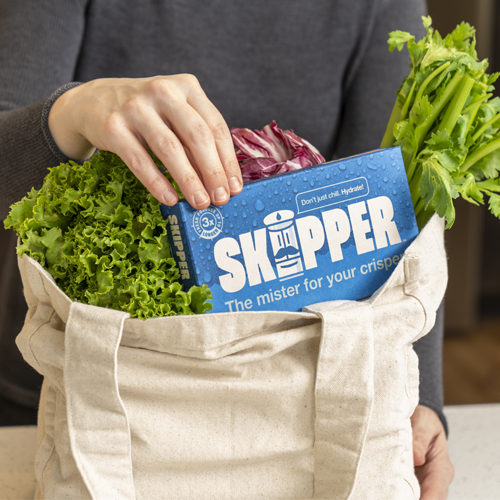 A shopping bag full of fresh veggies with a hand removing a Skipper.